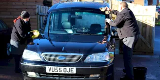 Hearse being cleaned by multiple people